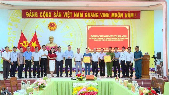 Phó Chủ tịch UBND tỉnh Nguyễn Tuấn Anh (thứ 10 từ phải sang) tặng quà của Tỉnh ủy, HĐND, UBND, Ủy ban MTTQ Việt Nam tỉnh cho lãnh đạo và Công an phường Hoài Nhơn Tây. Ảnh: Phi Long